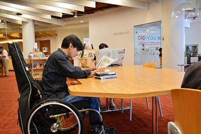 Patron using wheelchair accessible table in the library