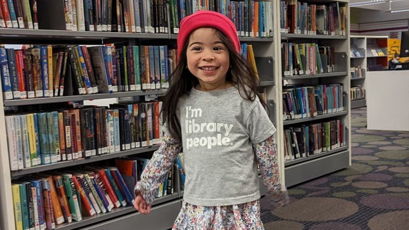 A child stands before a shelf of books