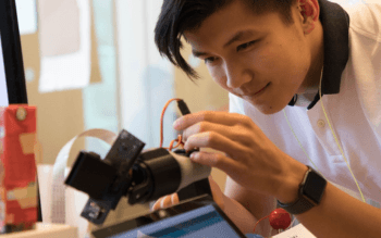 An attendee at the Maker Faire is tweaking a robotic arm