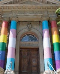 Toronto Public Library’s Yorkville Branch with transgender and rainbow flags wrapped on the pillars.