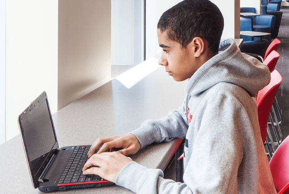 A student is using a laptop in a library branch.