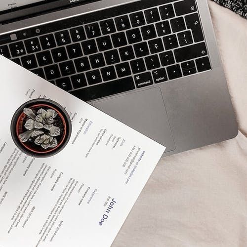 A resume is lying on top of a laptop keyboard.